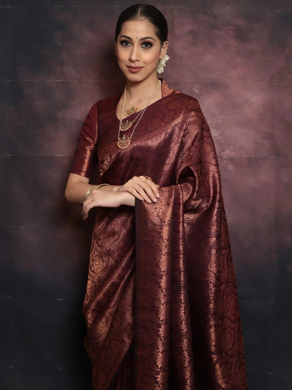 Woman wearing a maroon saree with a dark background